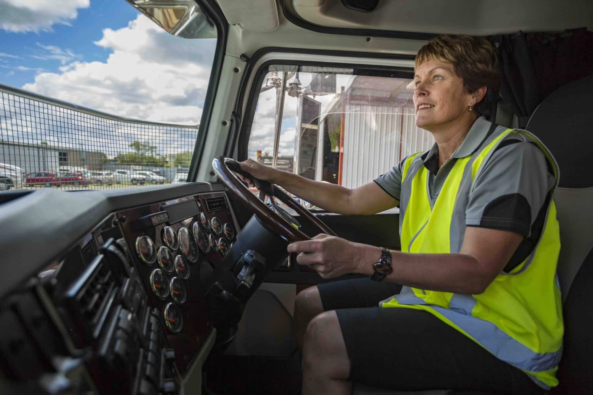 Happy Woman Driving a Truck Wearing Hi-Vis Clothes