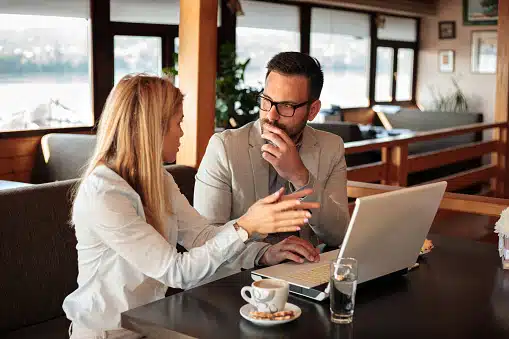 Two young male and female business partners having a meeting in a cafe