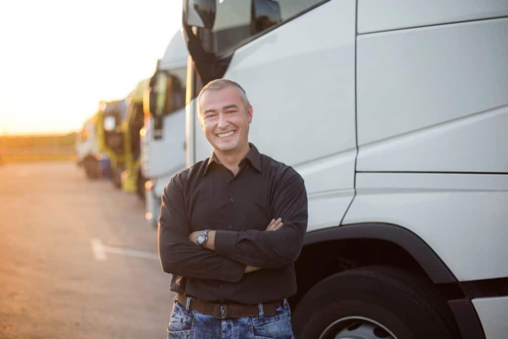 Confident light truck owner standing by his fleet, highlighting the importance of having reliable light truck insurance.